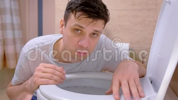 生病的男人在坐在地上的厕所里呕吐看着相机感冒视频的预览图