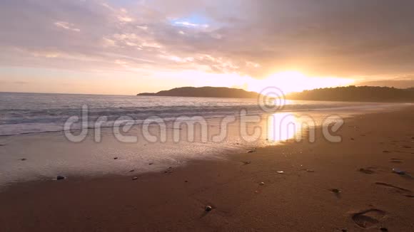 夕阳下平静而宁静的海浪拍打着荒芜的海滩视频的预览图