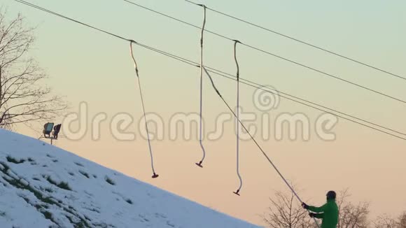 在滑雪胜地的山墙上拉着滑雪者和滑雪板背景中日落的天空视频的预览图