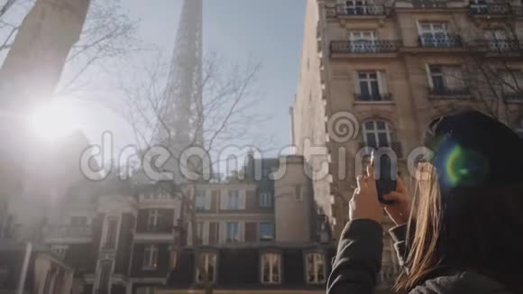 快乐美丽的旅游女性在巴黎度假时拍摄艾菲尔铁塔智能手机照片惊人的镜头耀斑慢动作视频的预览图