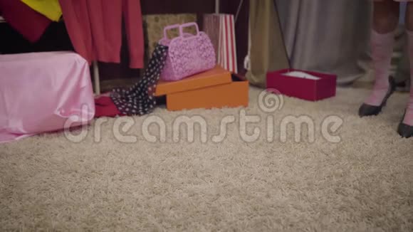 穿着粉红色袜子的小白种人女孩和穿着柔软地毯在室内行走的成年高跟鞋的特写双脚优雅的孩子视频的预览图