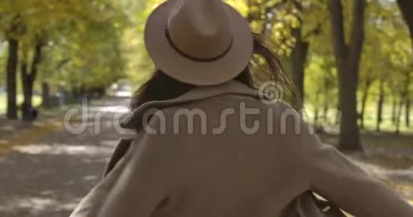 微笑的白种人女孩戴着优雅的帽子在秋天的公园里旋转迷人的欧洲女人带着愉快的微笑和棕色视频的预览图