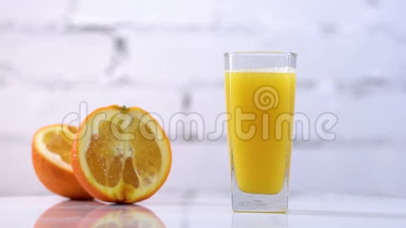 鲜榨橙汁放在一张桌子上旁边放着几片橘子带有水果的新鲜黄色饮料视频的预览图