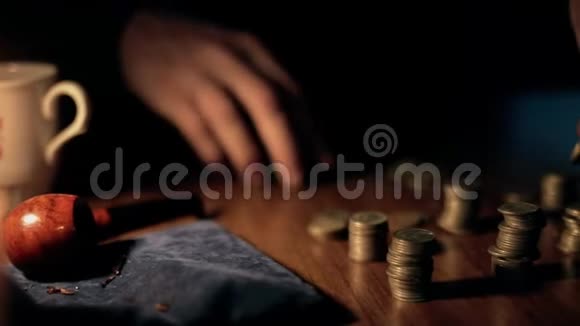 一位老人在桌子上数硬币蜡烛在燃烧贫穷和无助的概念视频的预览图