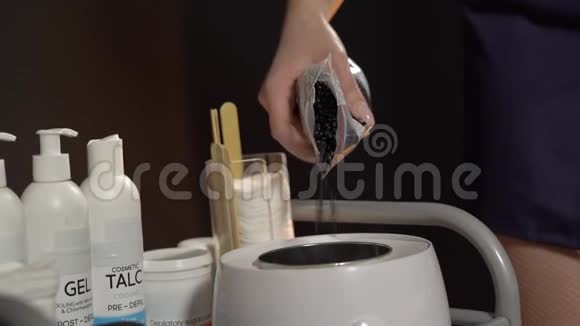 脱毛大师将硬蜡倒入碗中加热打蜡和糖膏的概念视频的预览图