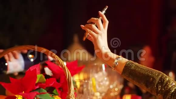 一个拿着手机女人在一个聚会上的夜总会里自拍很亮鲜花和装饰在前景中视频的预览图