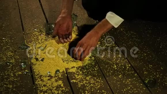 一个白人男人的手从地板上拿起一张黄色小米的特写在碎玻璃旁边视频的预览图