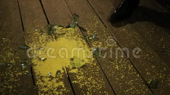 一个白人男人的手从地板上拿起一张黄色小米的特写在碎玻璃旁边视频的预览图