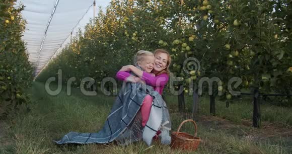 母女俩坐在苹果园里拥抱着微笑着4k视频的预览图