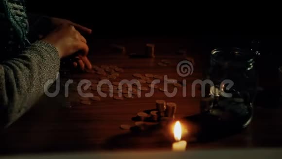 一位老人在桌子上数硬币蜡烛在燃烧贫穷和无助的概念视频的预览图