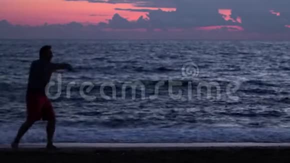 日落时在海滩上练习跆拳道的剪影视频的预览图
