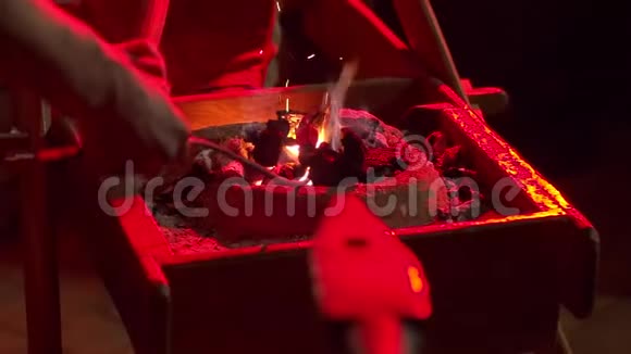 无法辨认的人锻造刀片从燃烧的余烬中拉出一块热金属视频的预览图