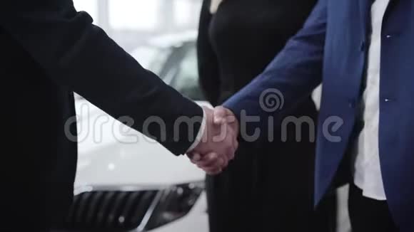 在汽车经销店里不可辨认的男人握手高加索交易员在展厅中与中东客户握手视频的预览图
