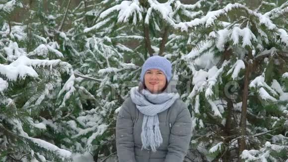 快乐的女人在冬日的松林中缓慢地抛雪视频的预览图