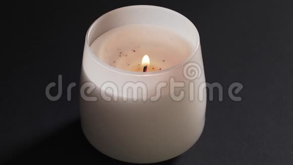 玻璃中孤立的美丽的白色蜡烛在黑色背景上燃烧在中心希望之火信仰之火视频的预览图