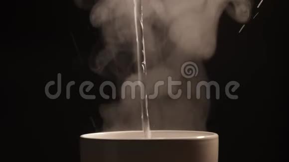 热开水倒入白色陶瓷杯或黑色背景上的杯子视频的预览图