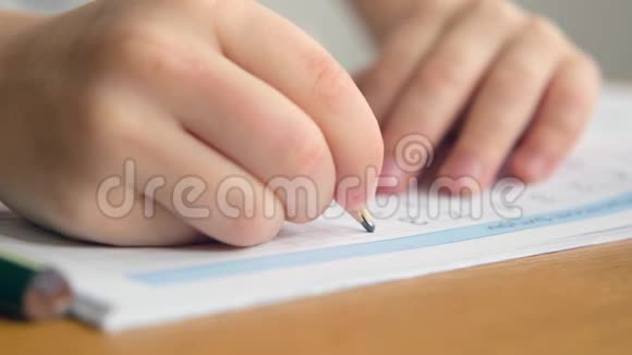 学龄前男孩蹒跚学步拿着铅笔在桌子上写字或做作业双手合拢视频的预览图
