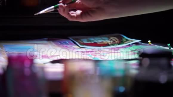 女人用刷子在织物上手绘的特写夜总会里的灯光视频的预览图