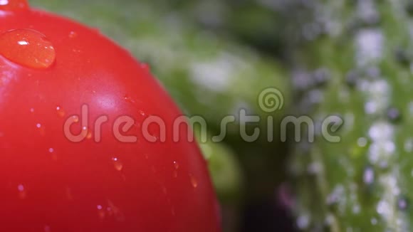 一滴水顺着红鲜番茄流下一个静态的宏观镜头绿色黄瓜的背景美丽视频的预览图