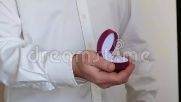 男人拿着粉红色的盒子带着结婚戒指准备向爱的女人求婚关上视频的预览图