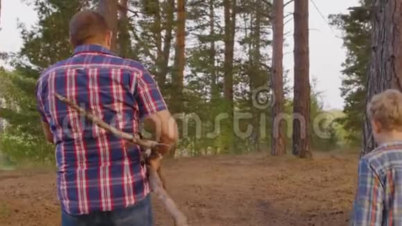 父亲和儿子在森林里扛柴火的背影视频的预览图