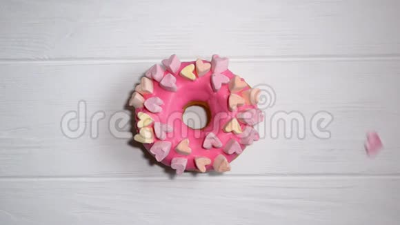 装饰的心落在粉红色的甜甜圈上带着糖霜和装饰带着心视频的预览图