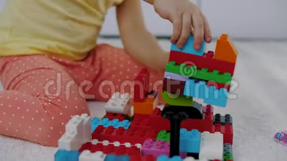 小女孩坐在地毯上用五颜六色的乐高积木组装房子视频的预览图