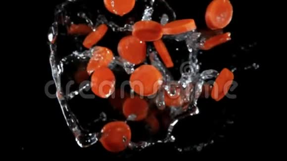 新鲜的胡萝卜在黑色的背景上随着水的飞溅而飞视频的预览图