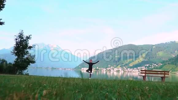 一位迷人的年轻女子在做一个瑜伽姿势以保持平衡并在Zellam湖附近伸展视频的预览图