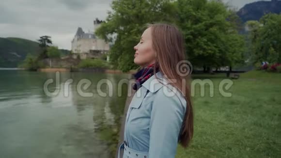 安纳西湖岸边站着一个迷人的女孩她穿着蓝色的外套看上去视频的预览图