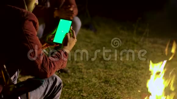 一个人用绿色屏幕看着这部手机视频的预览图