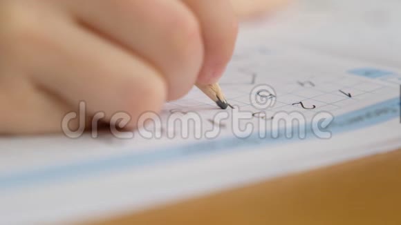 学龄前男孩蹒跚学步拿着铅笔在桌子上写字或做作业双手合拢视频的预览图