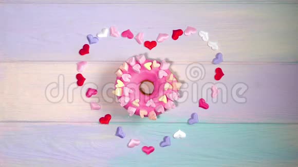 在彩虹的背景下女性手从装饰的心中取出粉红色的甜甜圈视频的预览图