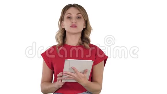 穿着红色t恤的女士手里拿着一块平板电脑一张严肃的脸在白色背景上和相机交谈视频的预览图