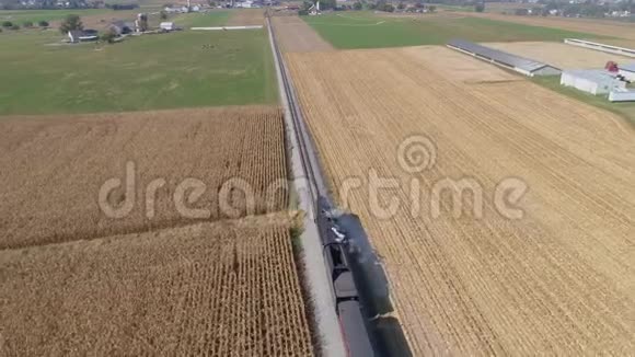 蒸汽火车吹烟和蒸汽沿着乡村旅行的鸟瞰图视频的预览图