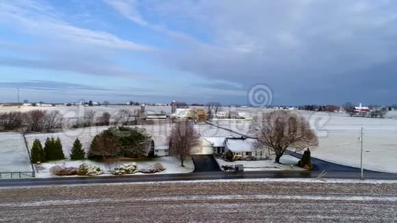 美丽乡村的空中景色以及一匹马和一匹马在经过一场轻雪后沿着这条路行进视频的预览图