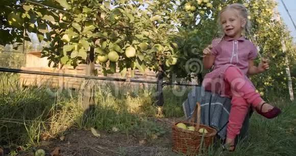可爱的金发小女孩微笑着在苹果园摆姿势4K视频的预览图