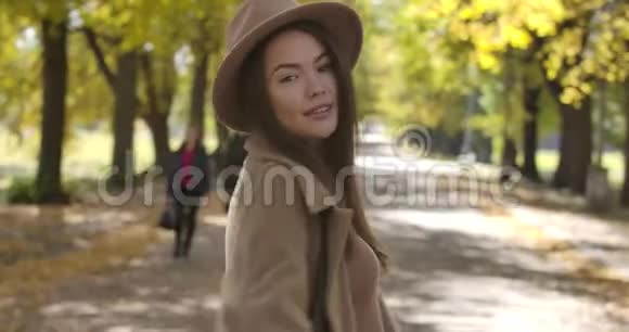 美丽的高加索女人戴着优雅的帽子在秋天的公园里旋转美丽的欧洲女人微笑愉快视频的预览图