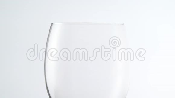 将红酒倒入白色背景的玻璃杯中在浅色背景下盛满酒精饮料的酒杯视频的预览图