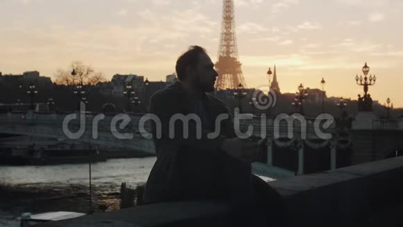 体贴帅气浪漫的游客男人坐在秋日塞纳河畔靠近巴黎埃菲尔铁塔的慢动作视频的预览图