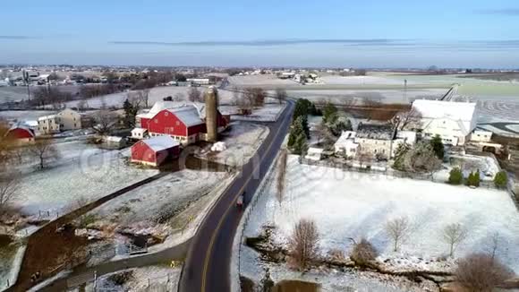 美丽乡村的空中景色以及一匹马和一匹马在经过一场轻雪后沿着这条路行进视频的预览图