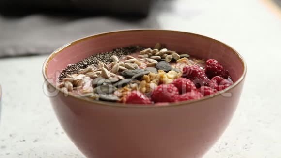 有人在吃覆盆子冰沙碗配麦片种子用汤匙特写素食早餐视频的预览图