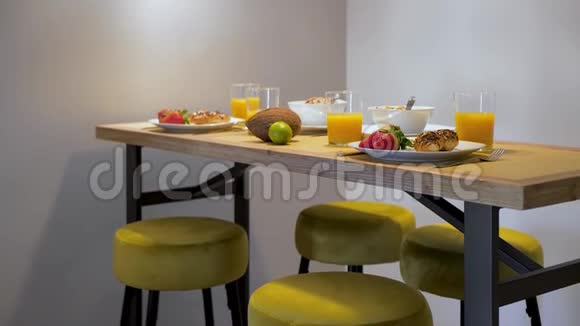家中早餐提供新鲜草莓牛角面包和橙汁供一对夫妇在木桌上享用视频的预览图