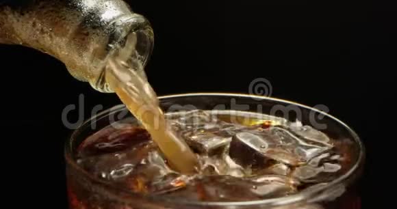 可乐正倒入一个装有冰块的玻璃杯中用黑色背景的红色进行宏观拍摄视频的预览图