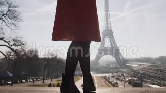 电影拍摄了美丽的白种人女士穿着红色的裙子摆姿势在日出时旋转埃菲尔铁塔天景慢动作视频的预览图