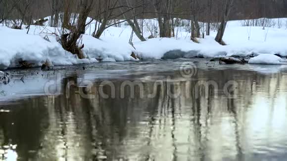 河中傍晚太阳的倒影河的雪岸流动的水经过融化的冰雪视频的预览图