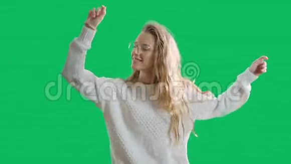 快乐的年轻女子在绿色的屏幕背景下跳舞和微笑积极的青少年女孩戴着彩色眼镜视频的预览图