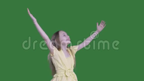 快乐的少女举起双手在绿色的背景上扭动微笑的女孩伸出双手享受快乐视频的预览图