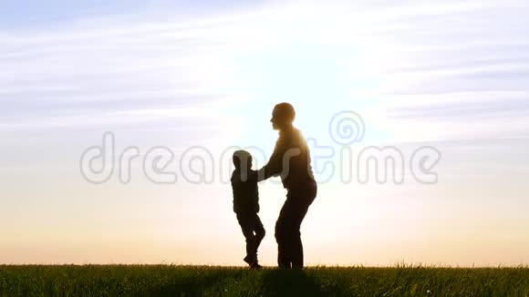 日落时分幸福家庭的剪影一个父亲牵着儿子手和旋转玩和玩视频的预览图