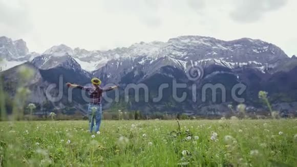 戴着花圈的甜美女人正在高山草地上散步快乐地双手旋转着视频的预览图